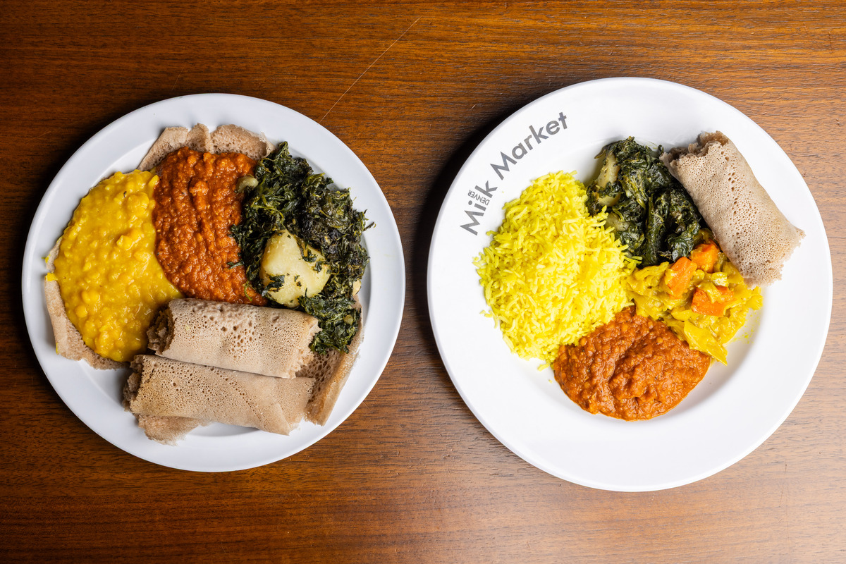 Two vegan Ethiopian plates from Konjo Ethiopian Food at Denver Milk Market, featuring lentils, greens, yellow rice, veggies, and injera on white dishes.
