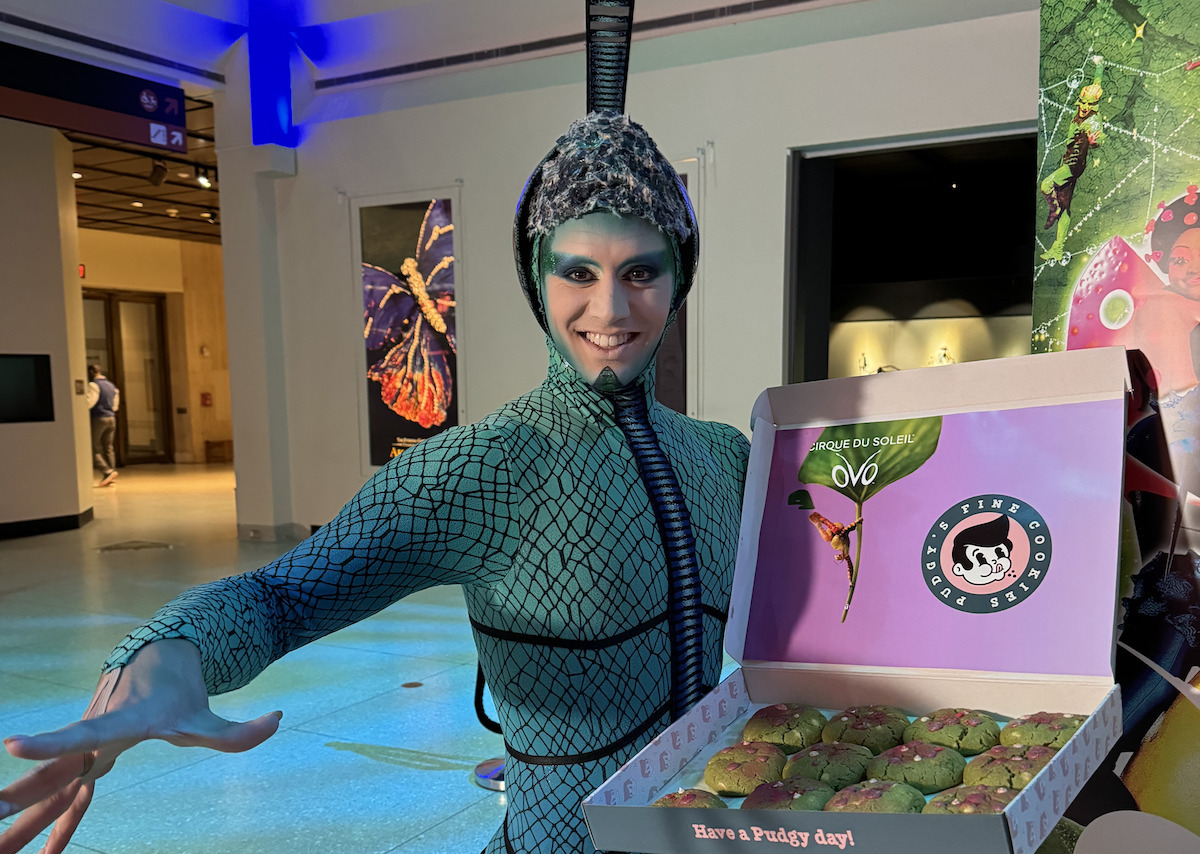 A Cirque du Soleil character from OVO poses with a box of Pudgy's cookies. | Photo by Pudgy's Fine Cookies