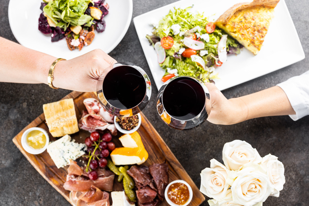 A toast over cheese and snacks at Mercat Bistro. | Photo by Harwood Hospitality Group