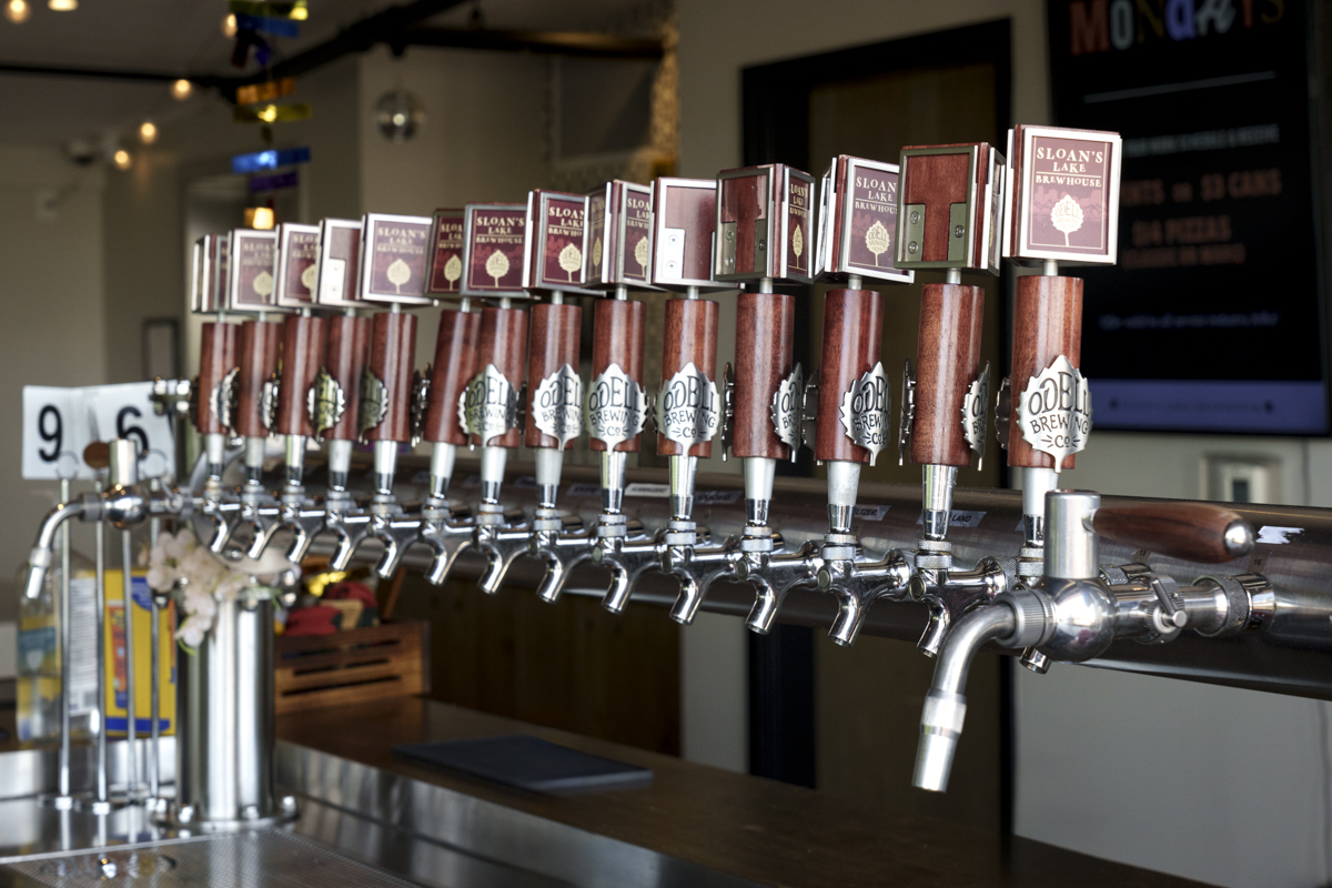 Row of Odell Brewing Company tap handles at Sloan’s Lake Brewhouse in Denver, Colorado, featuring custom wood taps lined up on a polished beer tower.

