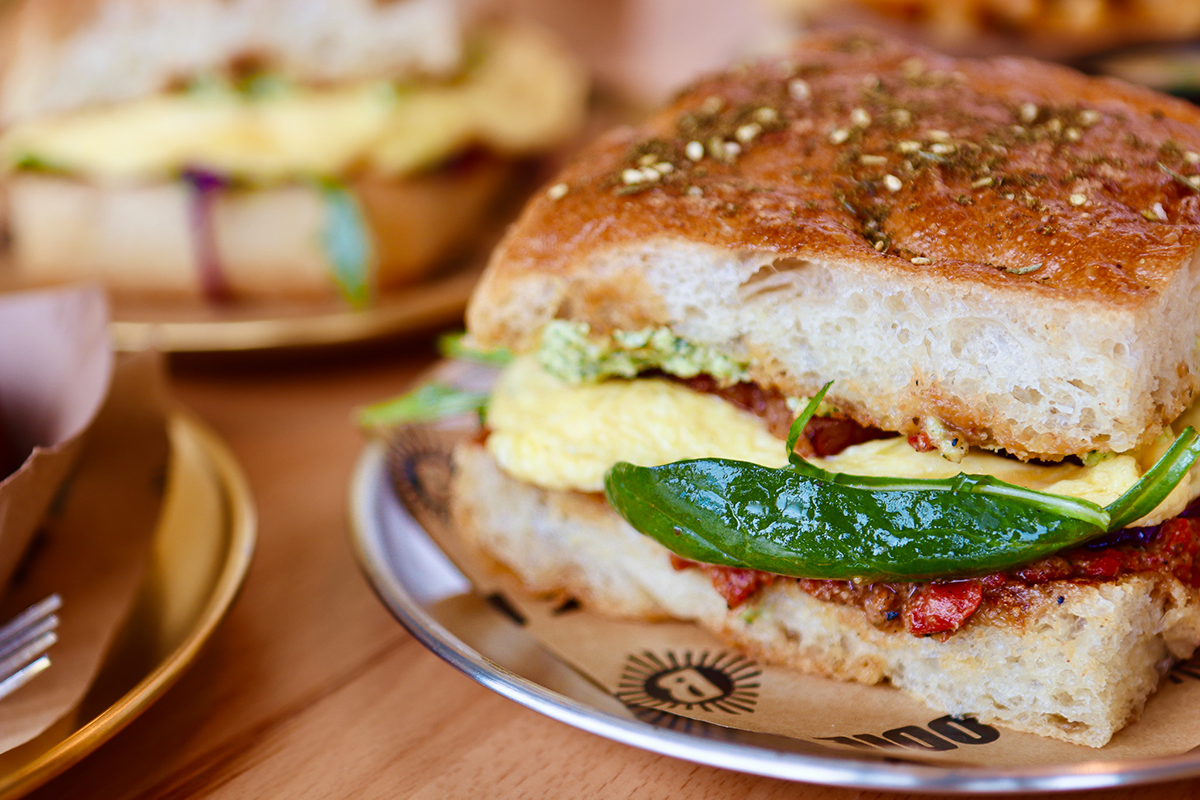 Odie B's breakfast sandwich features fluffy eggs, herbed spread, sun-dried tomatoes, and a whole green chile on thick focaccia bread.
