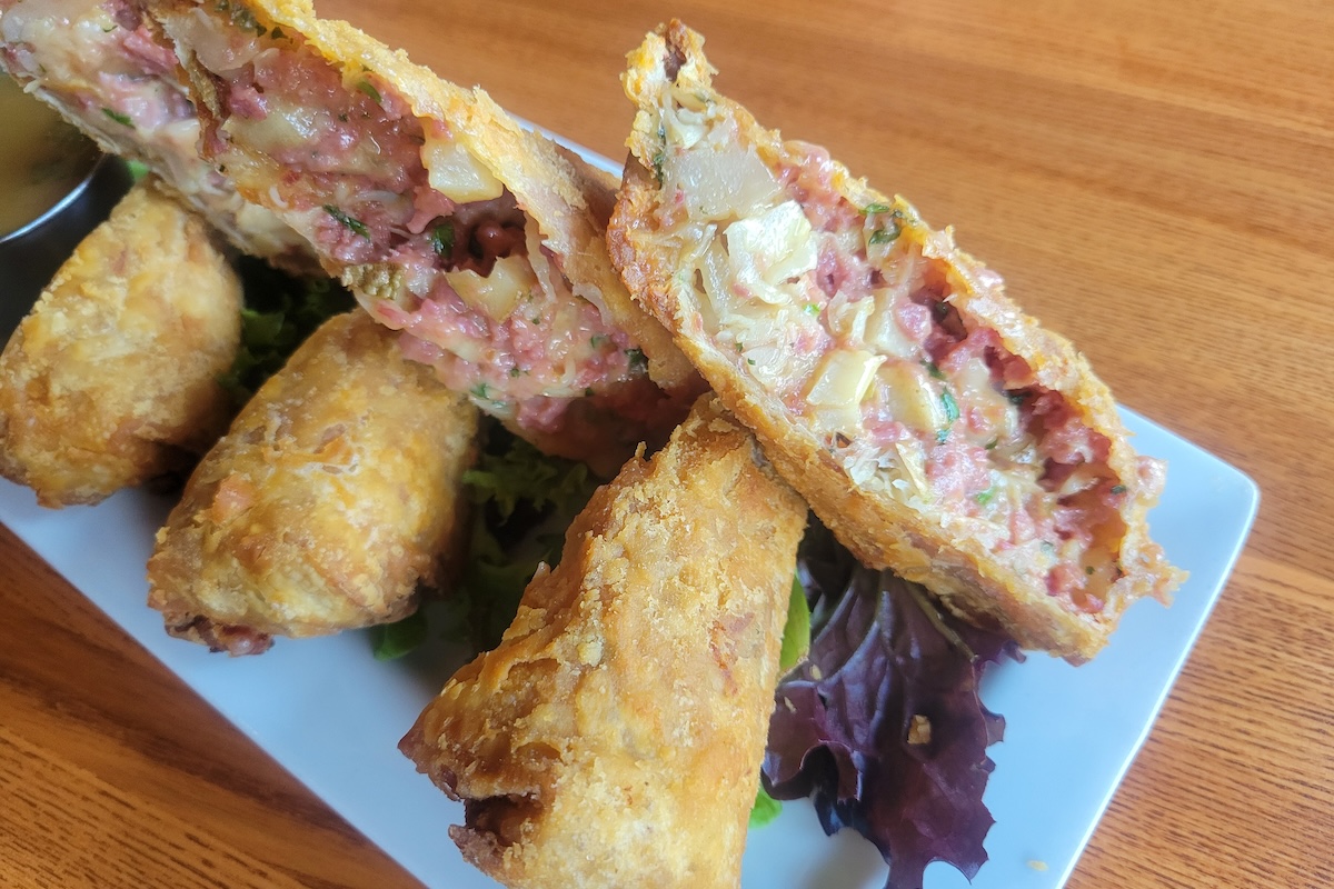 - DiningOut Global egg rolls stuffed with meat on a white plate