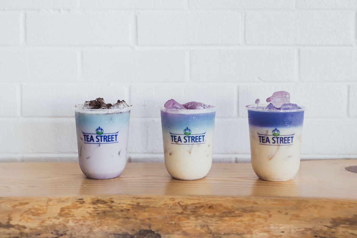 white wall with wood table and three cups of white and blue tea