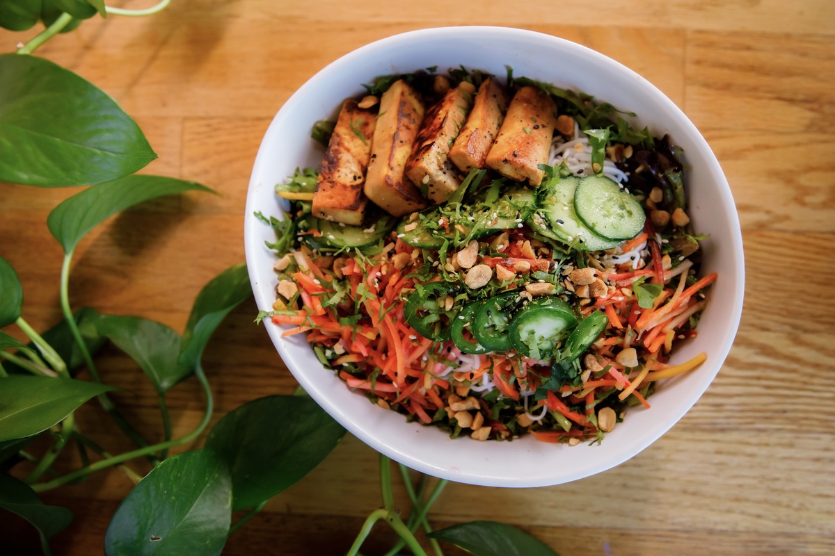 A vibrant Thai peanut salad at The Corner Beet in Denver, topped with grilled tofu, cucumbers, shredded veggies, jalapeños, and chopped peanuts.