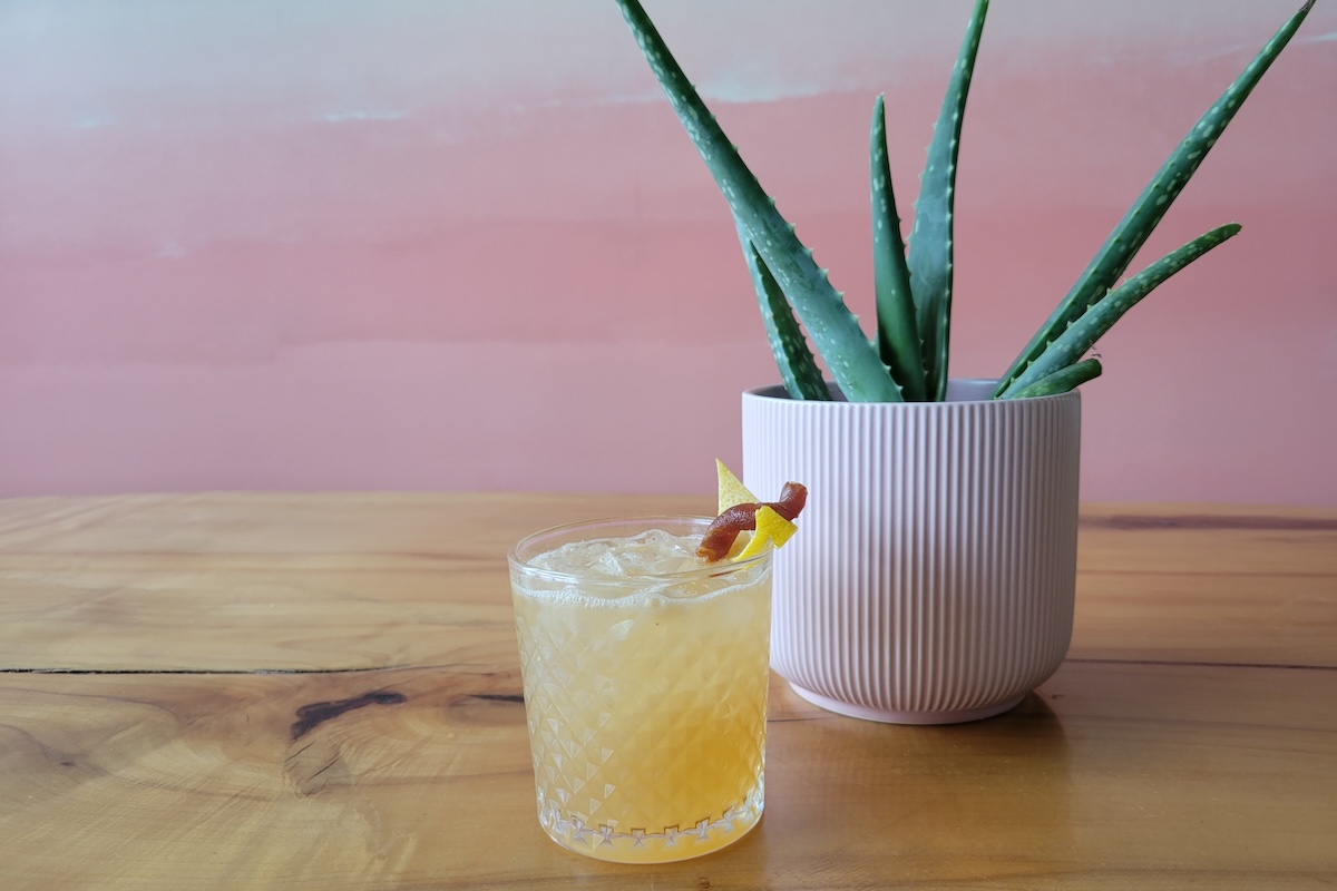 pink wall with plant and cocktail on wood table
