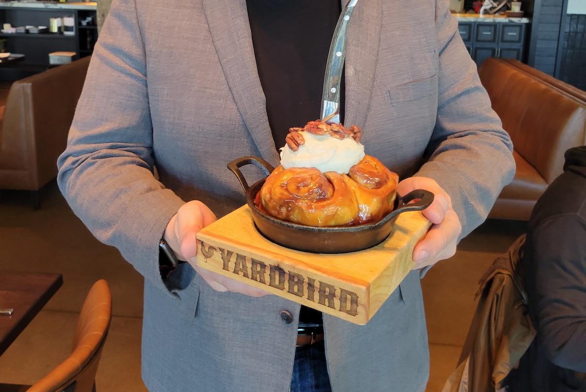 - DiningOut man holding giant cinnamon roll