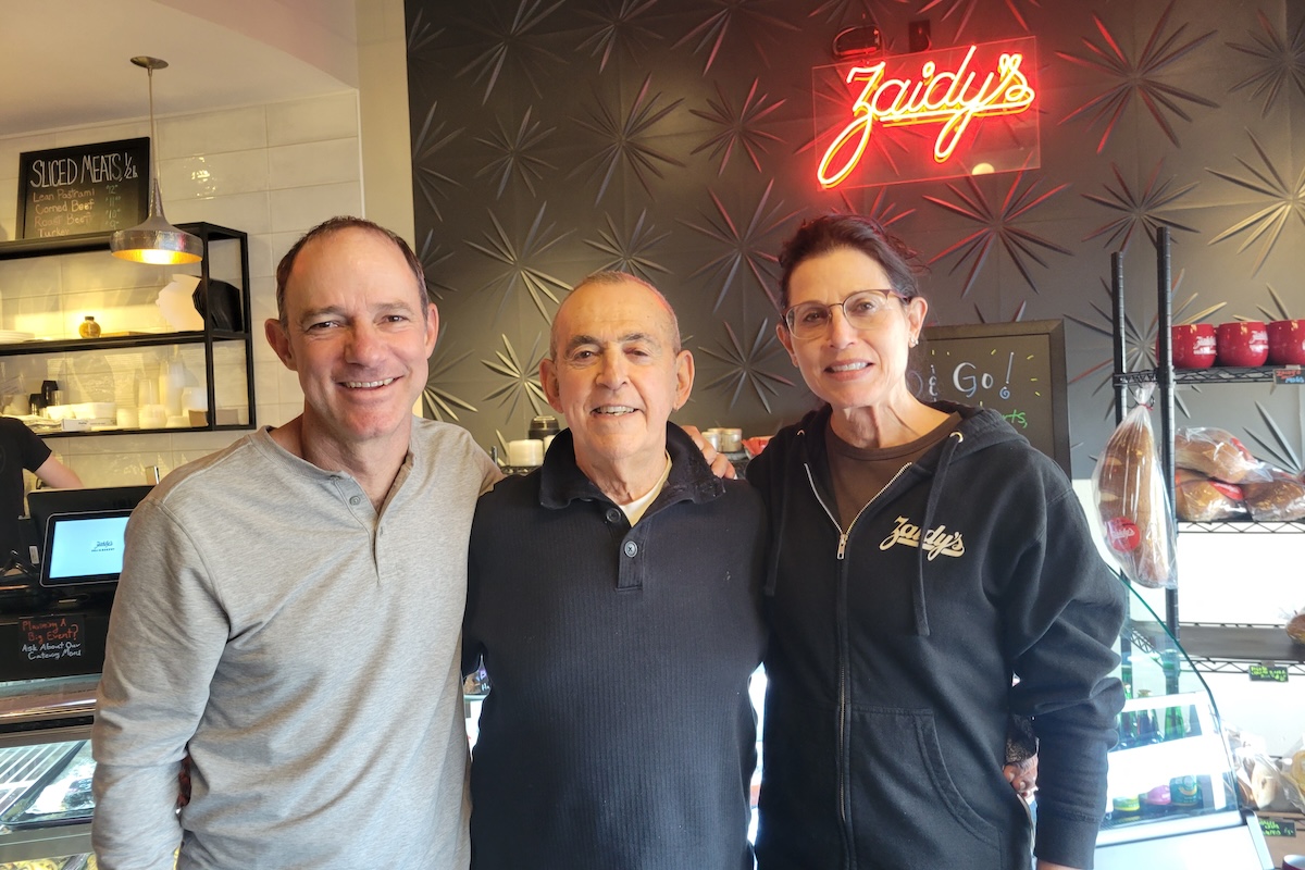 Three white people standing in front of zaidy's sigh