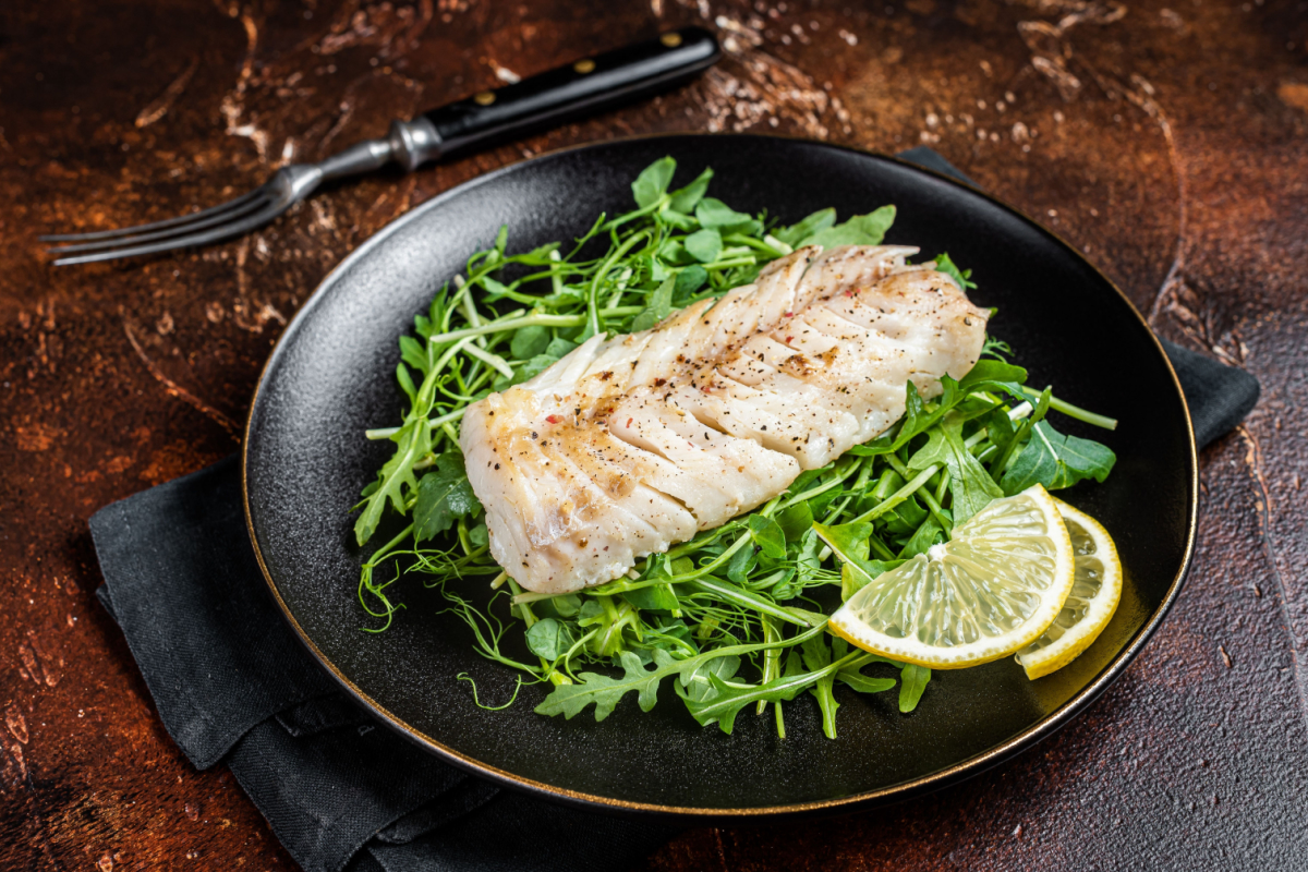 - DiningOut Grilled cod fish fillet served with green salad in a plate.