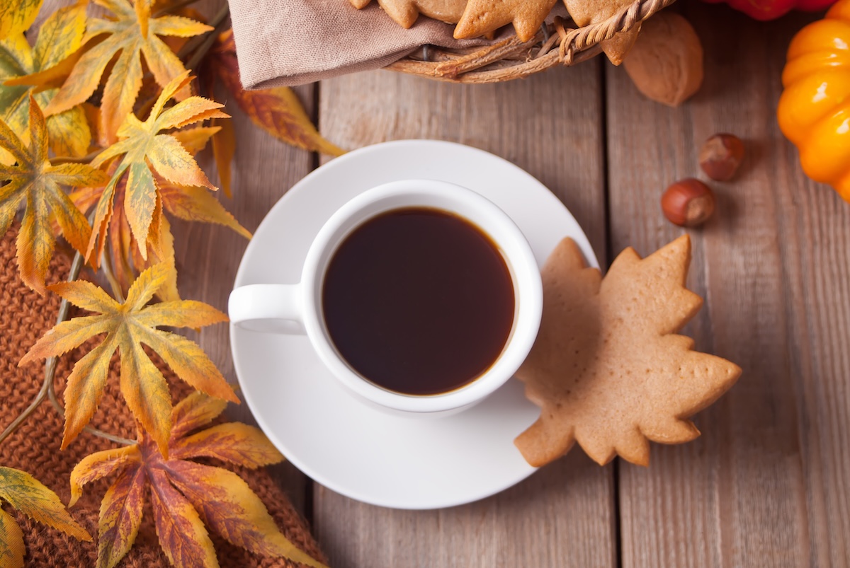 Cup of coffee autumn leaves pumpkin cookies on the wooden table Autumn harvest Autumn concept Top view