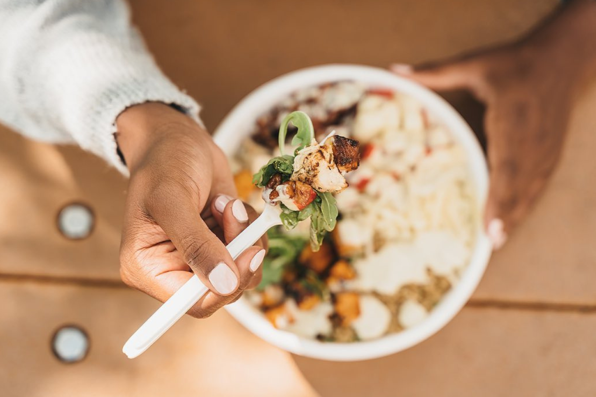 Close-up of a forkful of salad with grilled chicken, greens, and toppings from a harvest bowl at Crisp & Green in Denver.