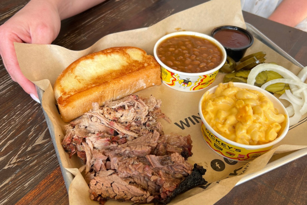 BBQ plate with sliced brisket, pulled pork, mac and cheese, baked beans, toast, pickles, and onions at Dickey’s Barbecue Pit in Denver.