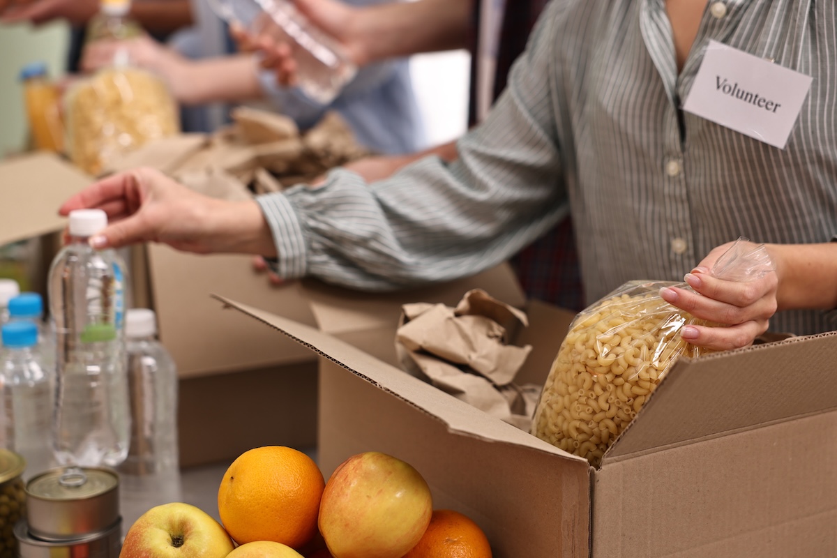 Volunteers packing food donations at table indoors closeup SNAP Denver