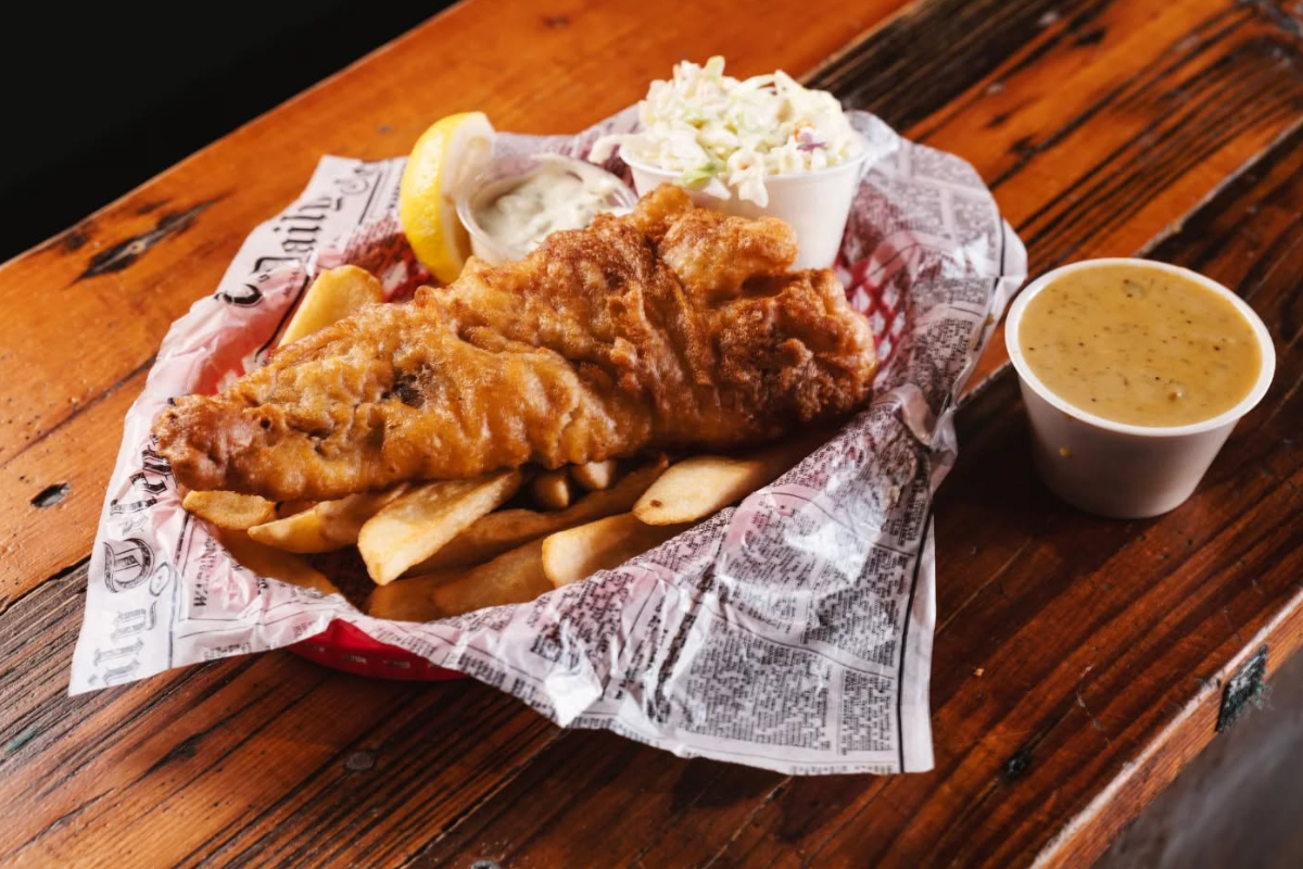 Basket of fish and chips served with coleslaw, tartar sauce, and lemon wedges at GB Fish & Chips in Denver.


