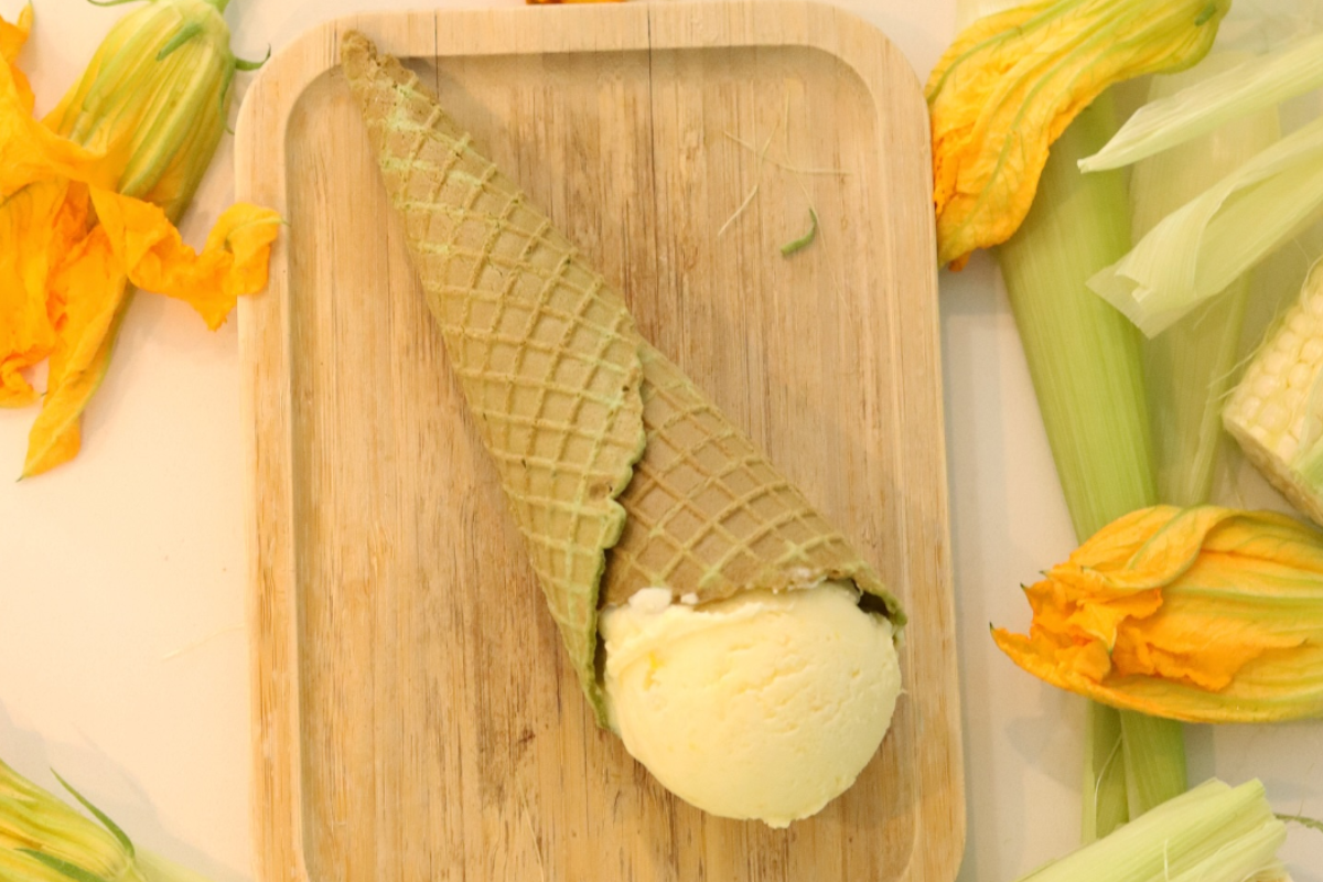 spaghetti-carbonara - DiningOut Corn bread gelato scoop in a green waffle cone on a wooden tray, surrounded by fresh corn husks and squash blossoms.