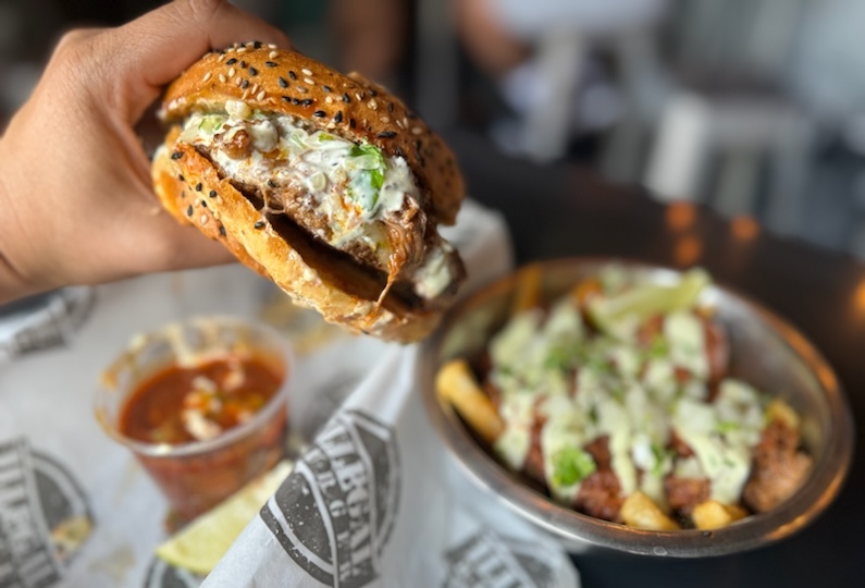 - DiningOut hand holding burger with dipping sauce