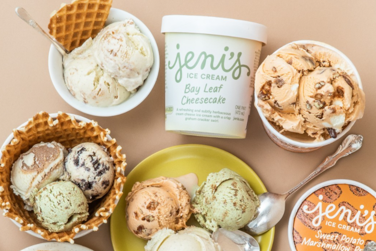 Multiple scoops of Jeni’s ice cream in bowls and cones, featuring flavors like Bay Leaf Cheesecake and Sweet Potato Marshmallow Pie on a beige background.