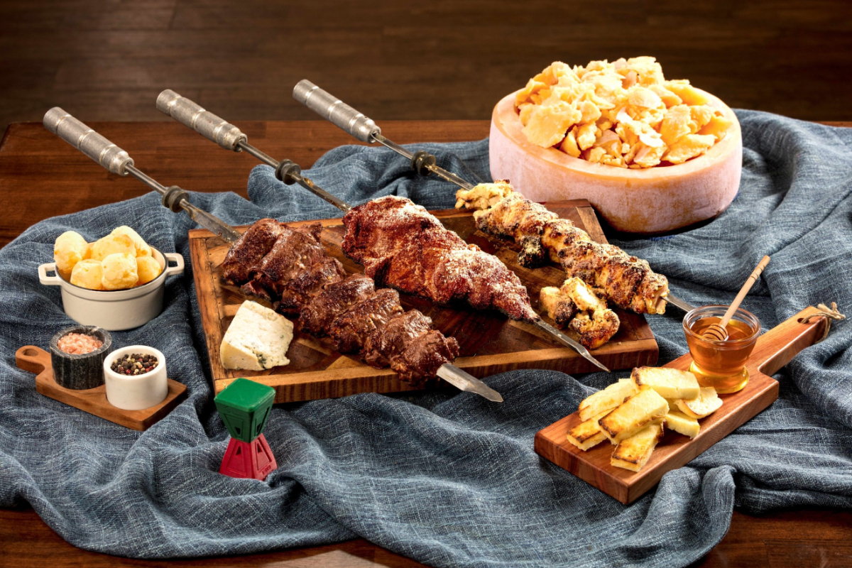 Churrasco-style grilled meat skewers, Brazilian cheese bread, grilled pineapple, and dipping sauces at Rodizio Grill in Denver.

