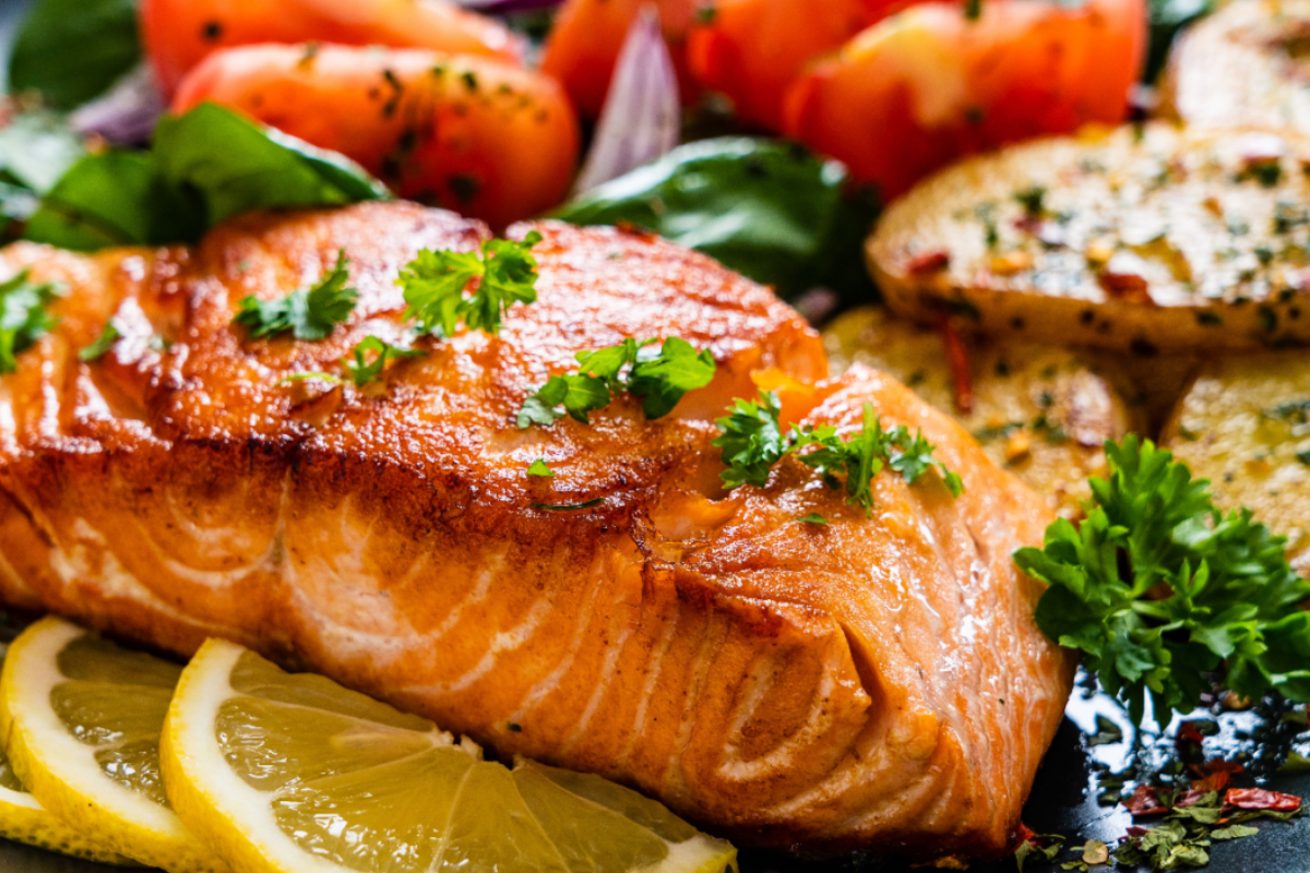 - DiningOut Pan-seared salmon fillet garnished with parsley, served with lemon slices, roasted potatoes, fresh greens, and tomatoes for a colorful and hearty meal.