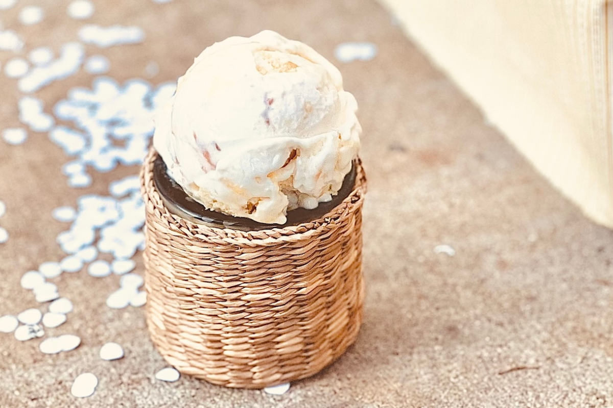 risotto-alla-milanese - DiningOut Single scoop of small-batch ice cream displayed in a woven holder on a neutral background, highlighting handcrafted texture and creamy swirl.