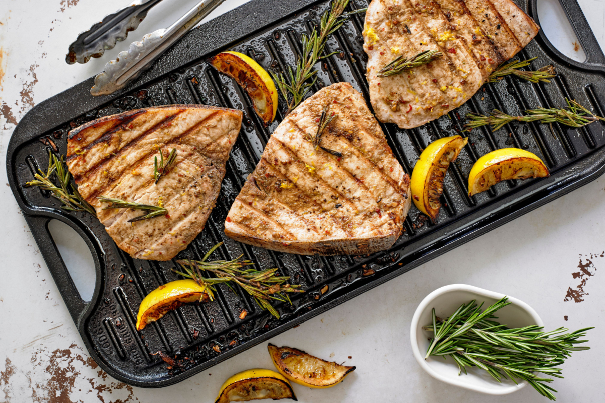 - DiningOut Grilled Marinated Swordfish Steaks with Lemon and Rosemary on cast iron grilling pan.