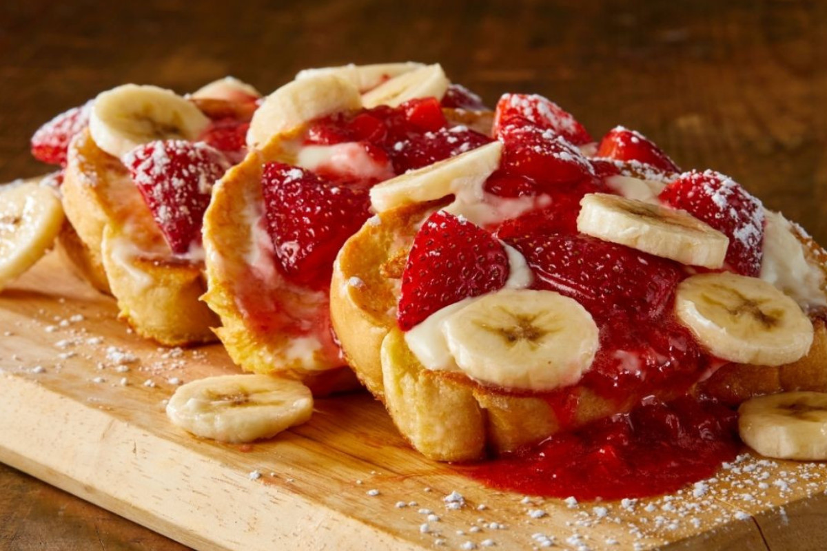 Thick-cut French toast topped with strawberries, bananas, cream, and powdered sugar at Village Inn in Denver.


