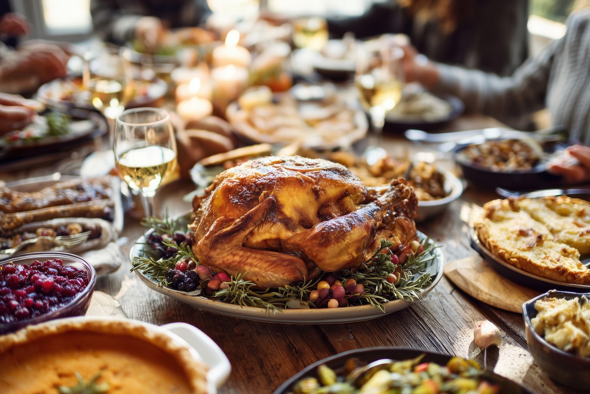 A beautifully arranged Thanksgiving dinner table featuring a roasted turkey at the center, surrounded by various side dishes and drinks. The warm atmosphere captures the essence of a festive gathering with family and friends. ai generated.