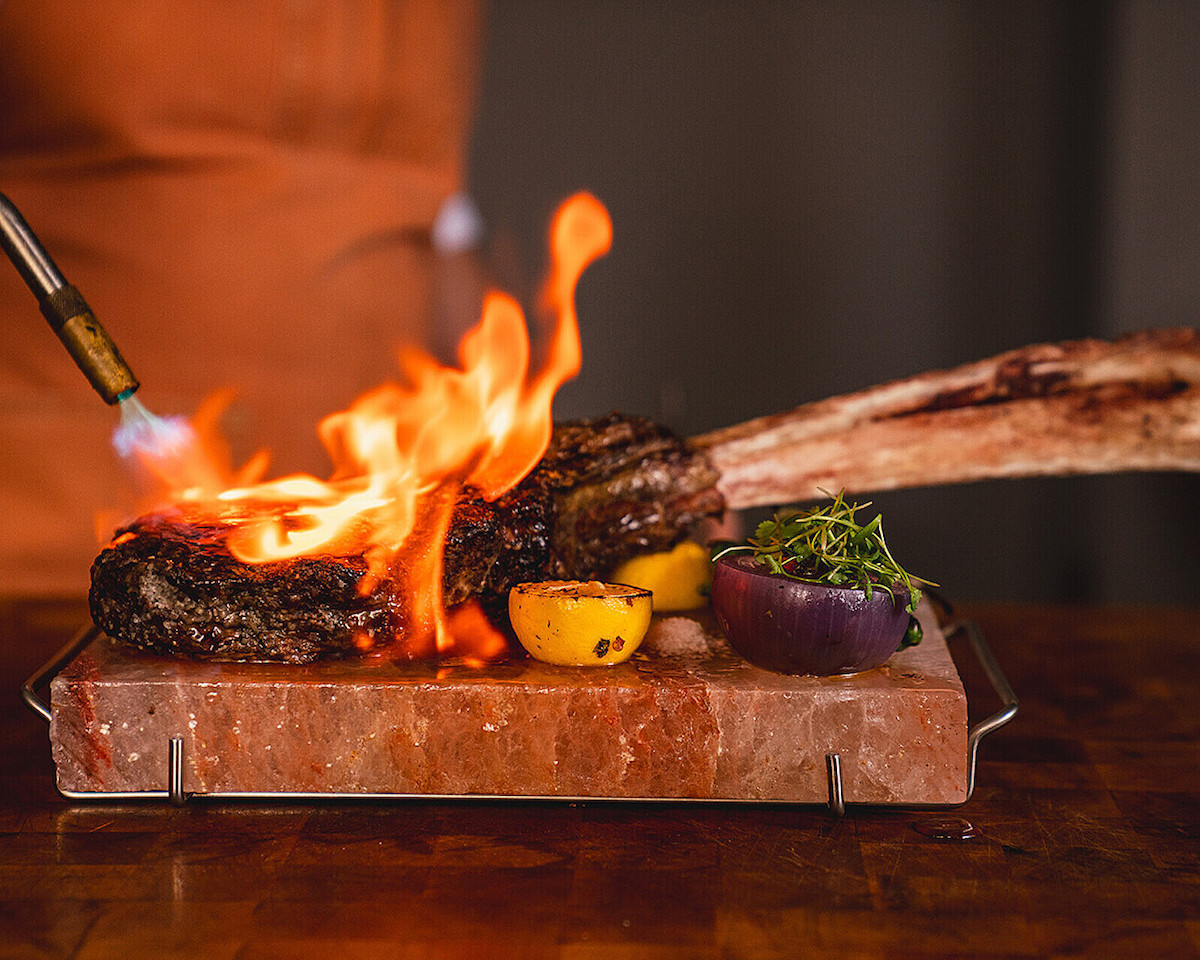 A steak gets torched tableside at Toro Toro. | Photo by Four Seasons Houston