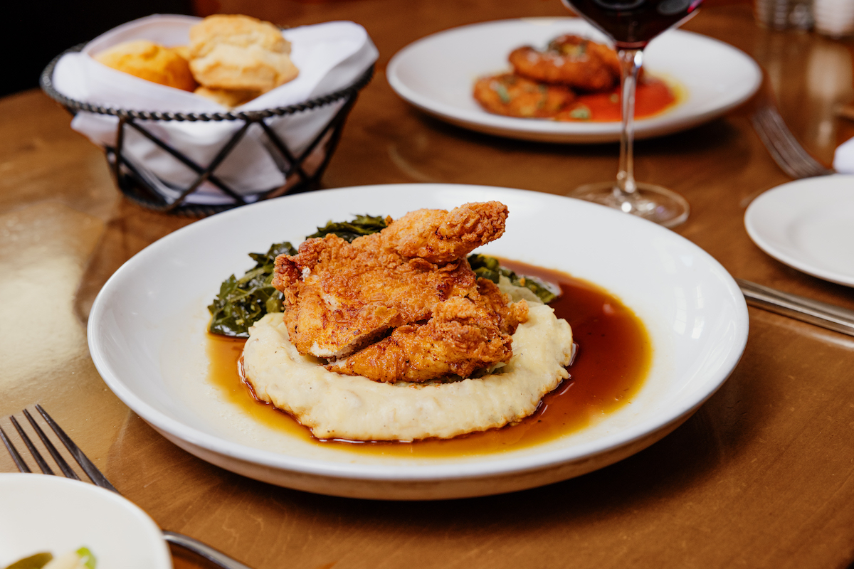 Fried chicken atop a bed of mashed potatoes and collard greens at South City Kitchen. | Photo by Fifth Group Restaurants