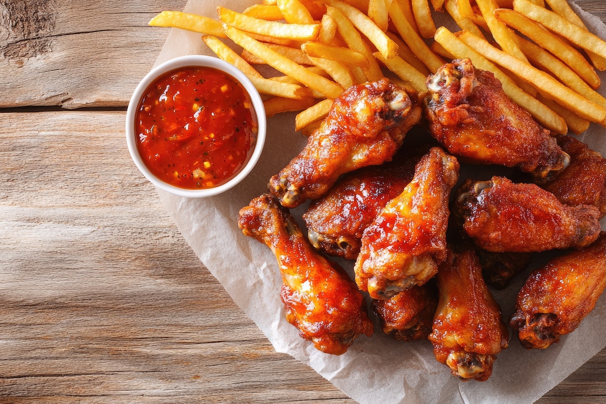 Spicy fried chicken wings with a side of fries, placed on parchment paper. By: amnart2521 ID: 254204404