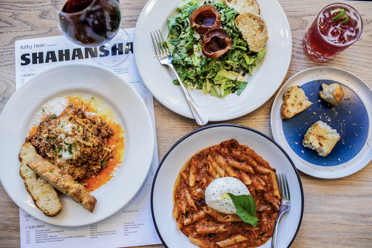 A spread of salad, pasta, wine, and cocktails at Kitty Dare. | Photo by Heidi Harris