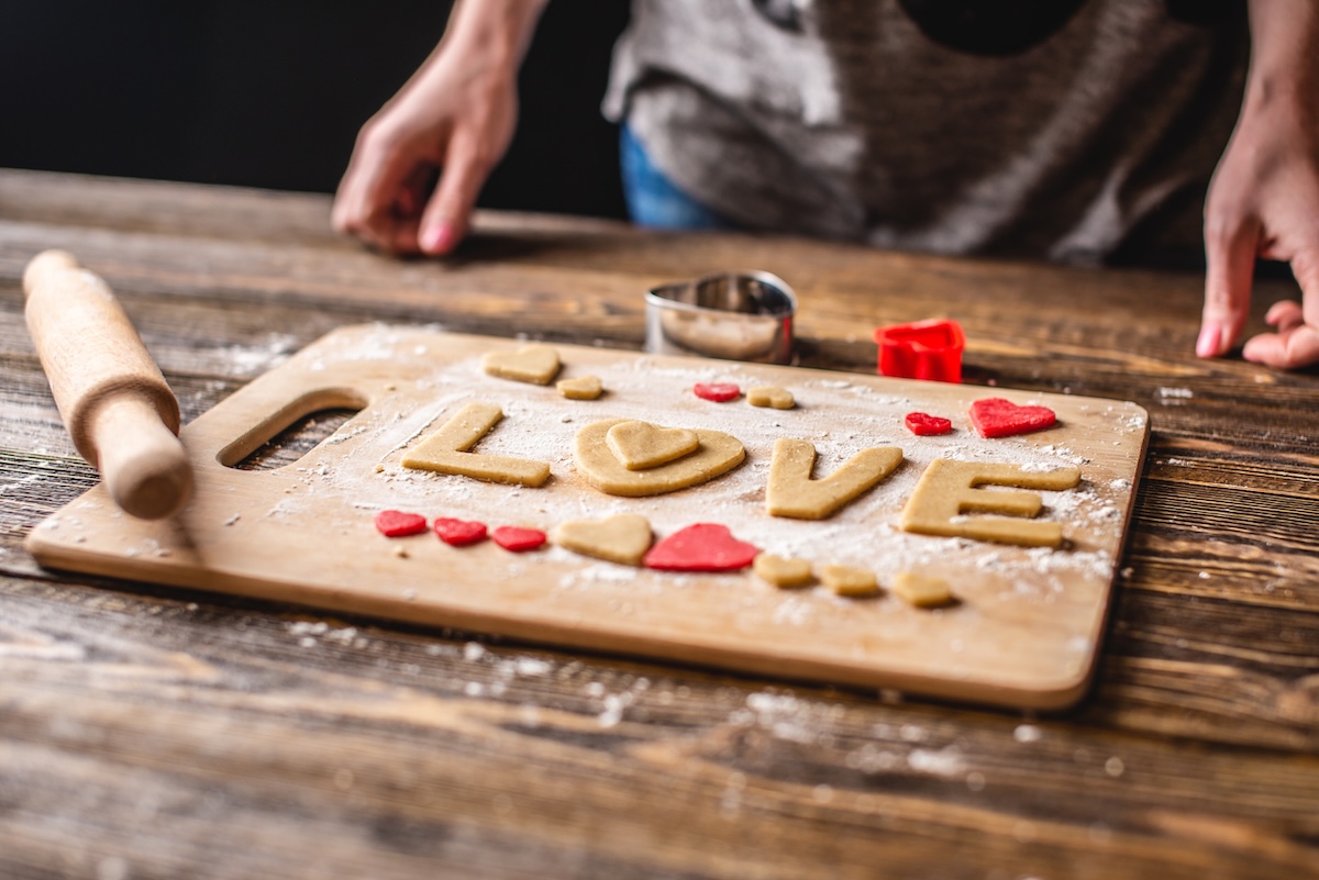 Cooking cookies from the dough in the shape of a heart and the word love on dark wooden background. Baking for Valentine's day and a romantic date ID: 137699941 by: artoleshko