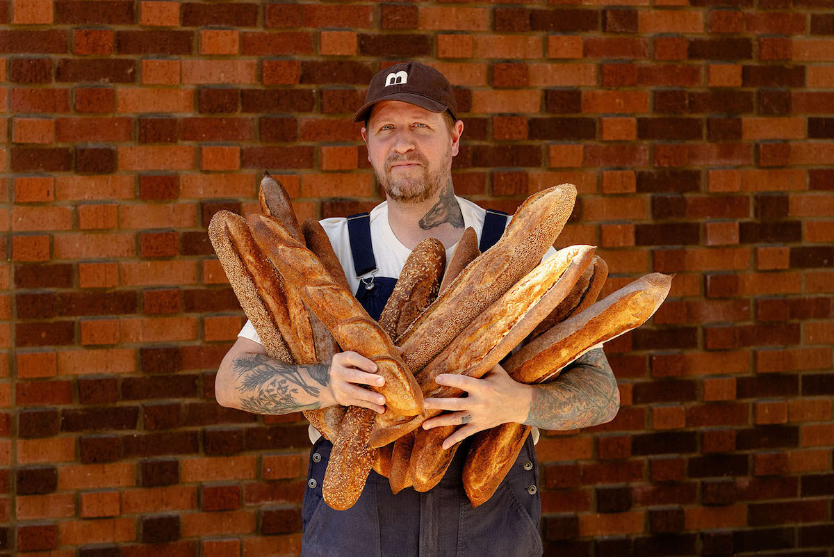 Peter Edris with armfuls of loaves at the Bread Club. | Photo by the Bread Club