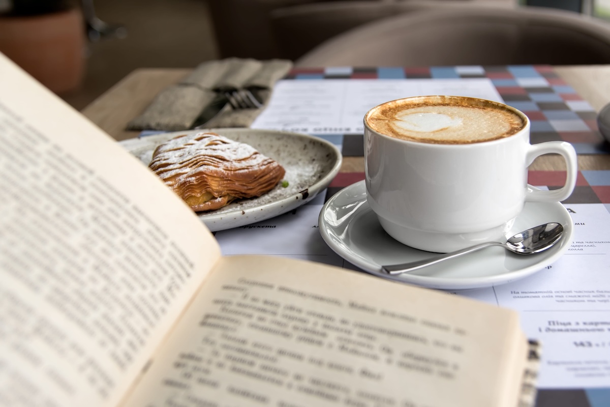Still life details, cup of Cappuccino and cake with book on table in coffee shop cafe, shallow DOF. NYC