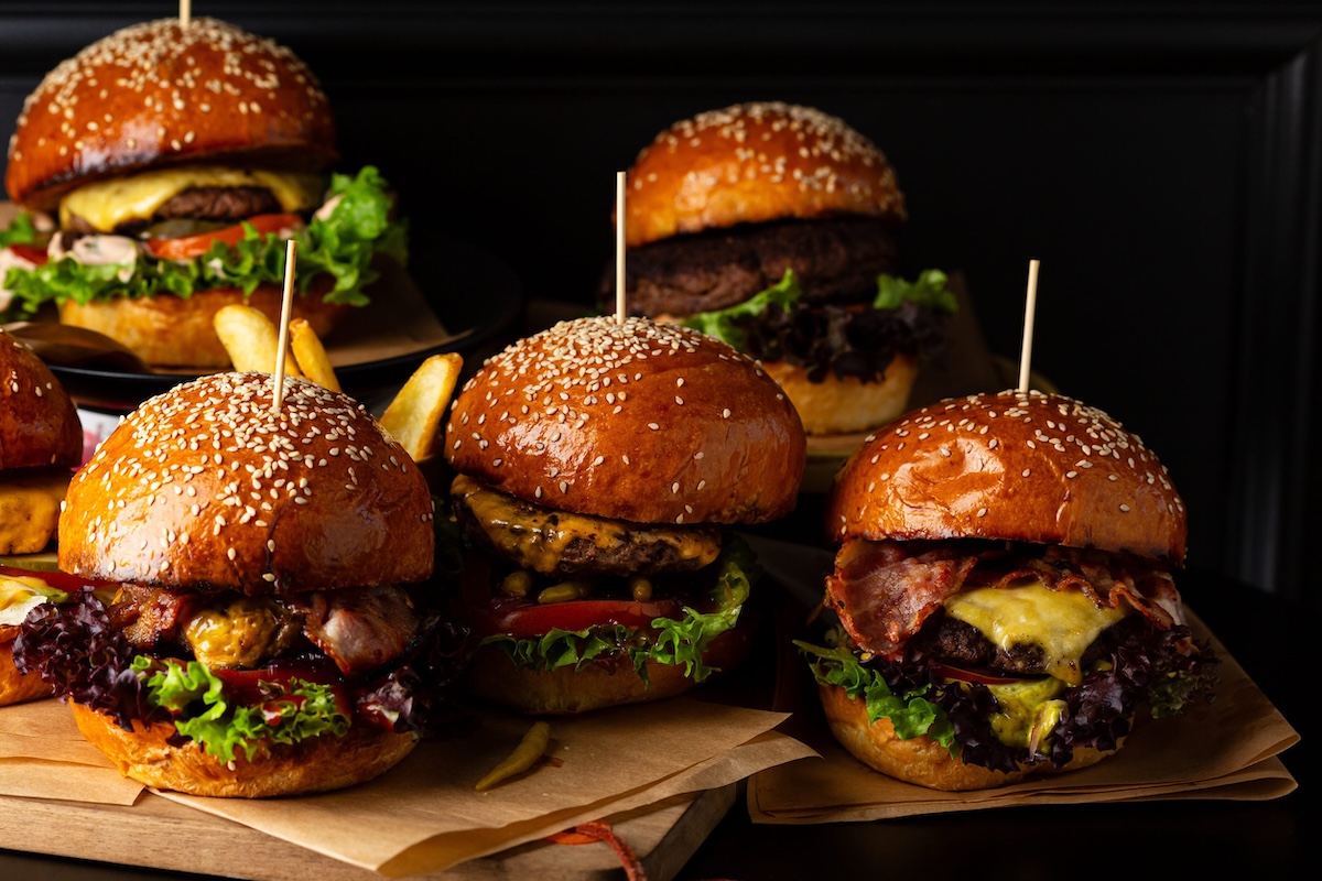 Set of different burgers on black table fast food background close up