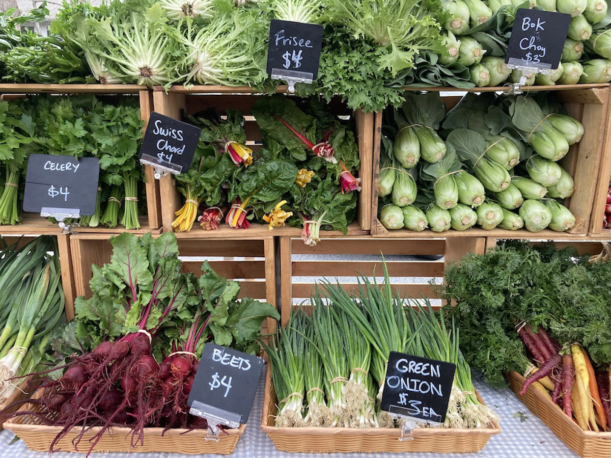 image2 - DiningOut Crates of frisée, bok choy, Swiss chard, beets and green onions line a vendor’s table with chalkboard signs with item names and prices at Morningside Farmers Market. | Photo by Morningside Farmers Market