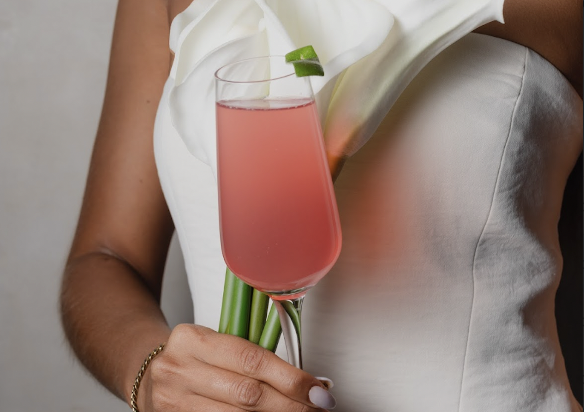 Atrium’s cocktail Ciudad 75 is held in a flute glass, with white lilies in the background. | Photo by Angie Webb
