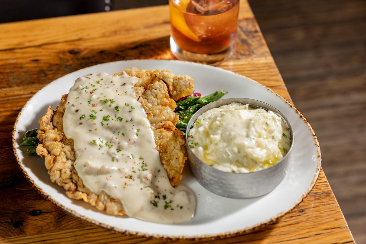 Chicken fried steak atop a bed of green beans, with mashed potatoes, at Haywire. | Photo by Kayla Enright