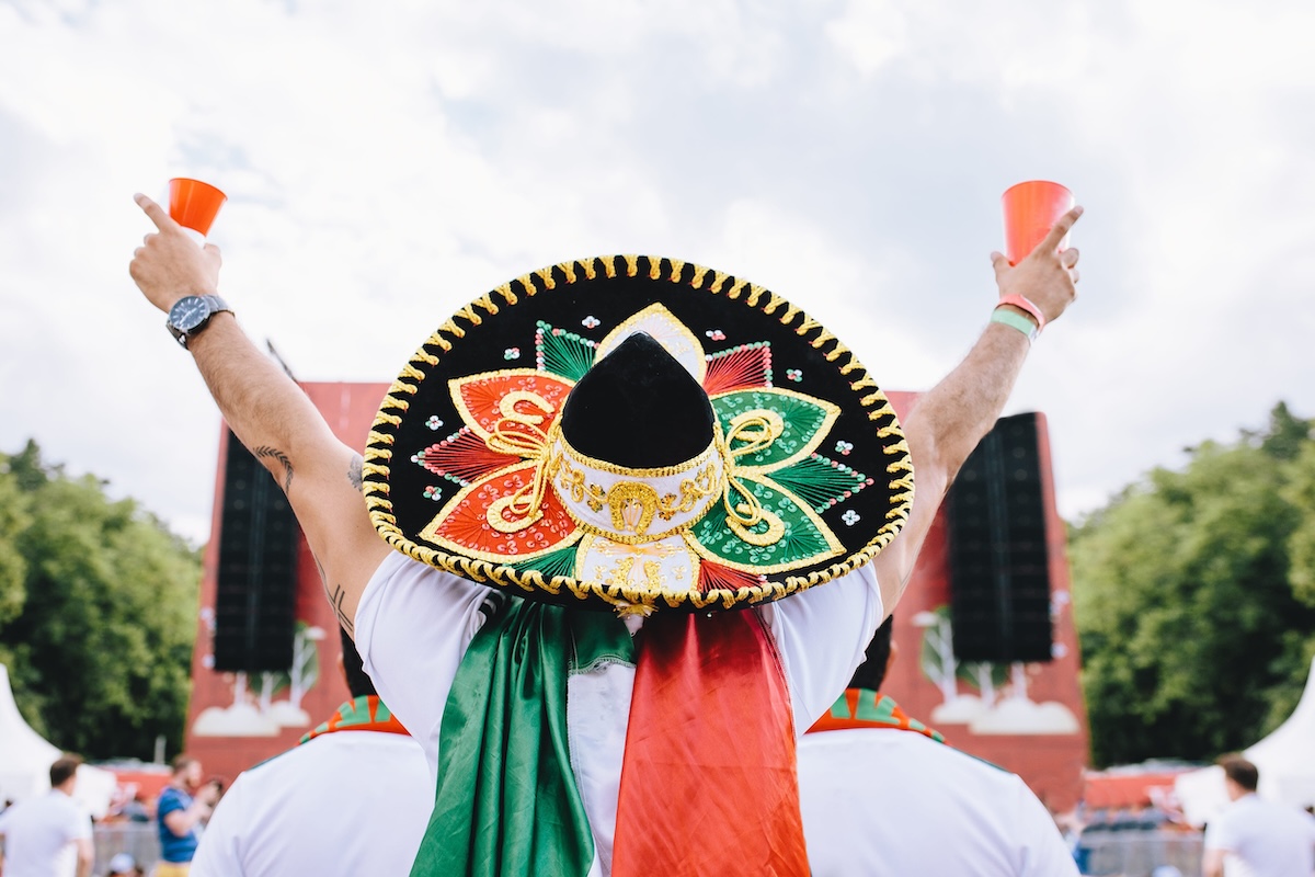 Mexican fans in uniform and sombrero are happy for their team during the World Cup. Horizontal