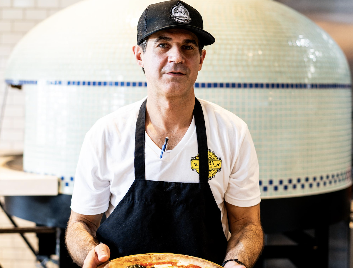 Chef Steven Ferdinand with his wood-fired pizza. | Photo by Flora d’Italia 