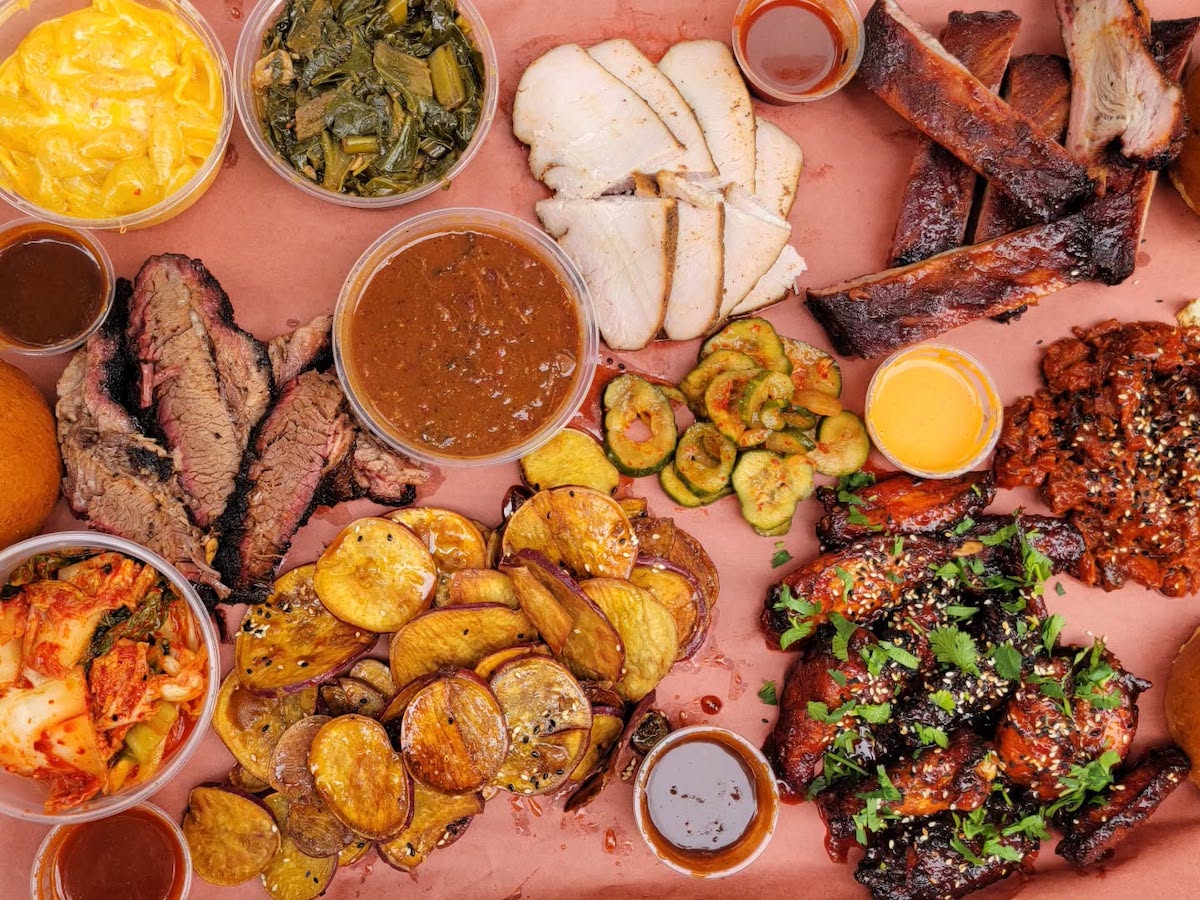 A spread at Heirloom Market BBQ showcases the signature Korean-Southern barbecue fusion, with smoked brisket, ribs, kimchi, wings, and classic Southern sides. | Photo by Heirloom Market BBQ