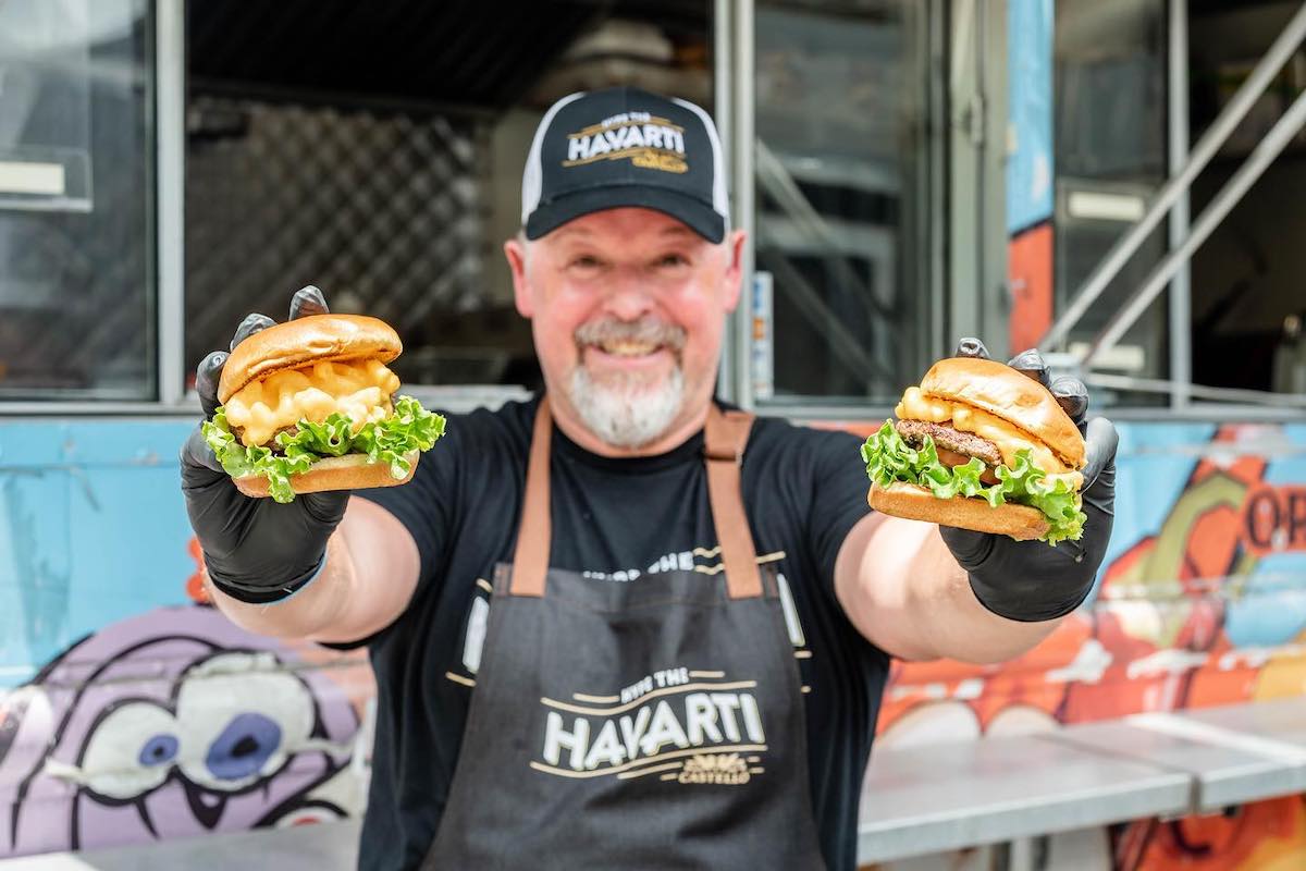 Michael Renner poses with a couple of burgers outside his Loaded Burger food truck. | Photo by Loaded Burger