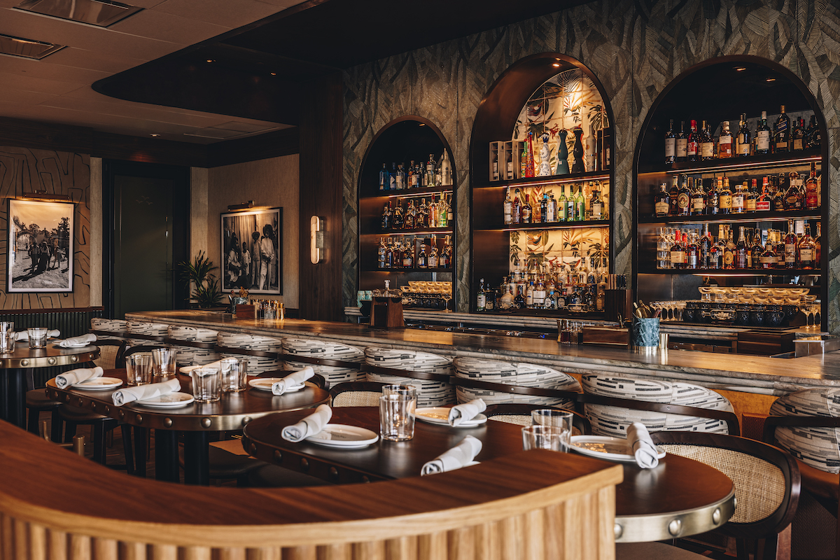 Maroma’s moody, resort-inspired dining room pairs tropical textures and warm wood tones with an expansive bar program designed to evoke the feel of a luxe coastal getaway. | Photo by Samantha Marie Photography