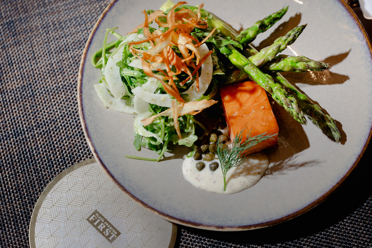 Plaza Premium First elevates the airport dining experience with refined dishes like salmon with asparagus and fresh greens served in a luxe lounge setting at DFW. | Photo by Plaza Premium Lounge