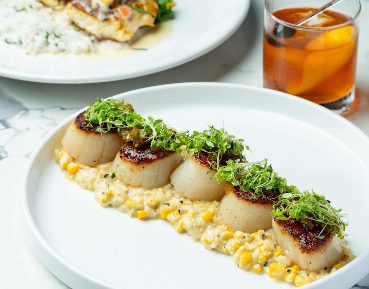 Pearl and Vine - DiningOut Seared scallops served over creamy corn risotto, topped with fresh microgreens at Pearl and Vine. | Photo by Pearl and Vine