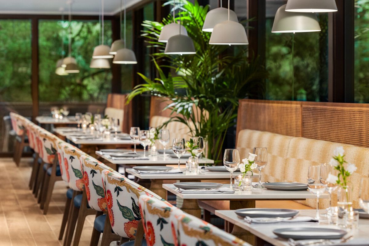 The bright, modern dining room with floral-upholstered seating and lush greenery at Harrison's at the Woodlands Resort. | Photo by the Woodlands Resort