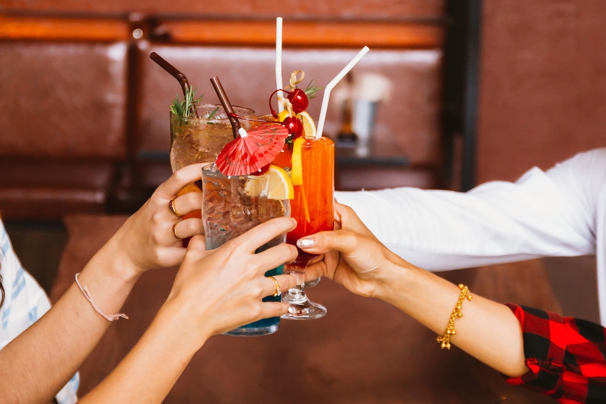 Close up of many friends hands holding a glass of alcoholic cocktail for social gathering and celebration in bar phoenix arizona bars