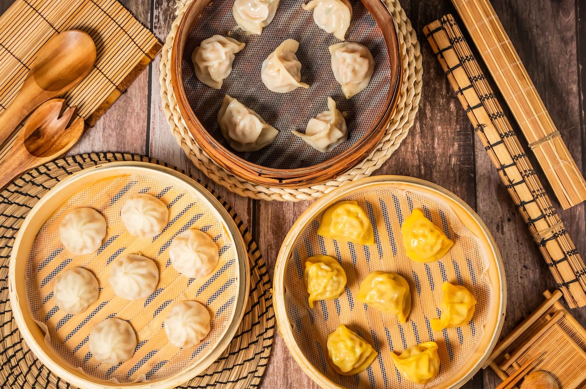 Assorted Steamed Shrimp Dumplings Verity with chopsticks and spoon served in bamboo steamer isolated on wooden table top view of taiwan food stock nyc