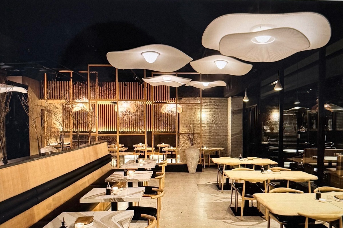 Harumi Sushi  interior with soft lighting, wavy ceiling lamps, and wooden tables and chairs | Photo by Grace Stufkosky and Kevin Brost