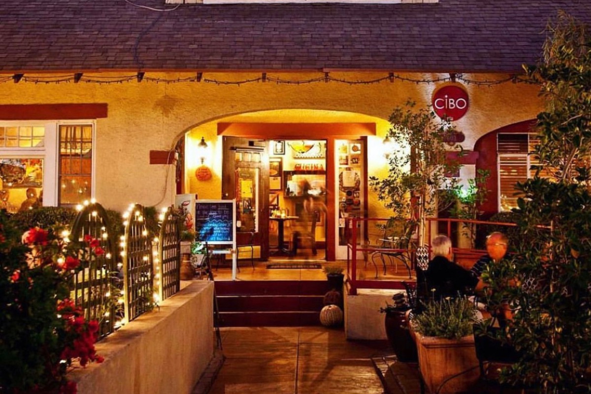 Cozy, warmly lit Cibo entrance at night with soft yellow lights. | Photo by Guido Saccone