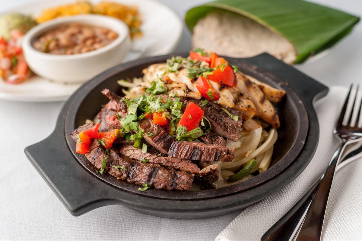 Cantina Laredo - DiningOut Cantina Laredo’s combination fajitas pair grilled steak and chicken with sautéed onions and peppers, served alongside rice, beans, and fresh tortillas. | Photo by Cantina Laredo